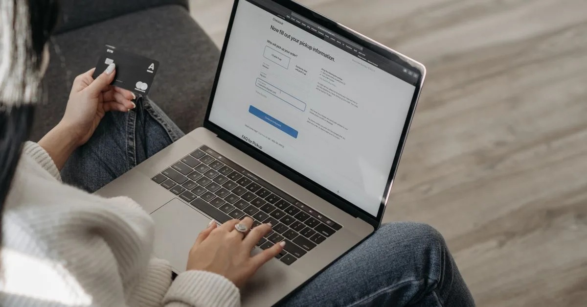 Kvinde handler online på sin bærbare computer med betalingskort i hånden